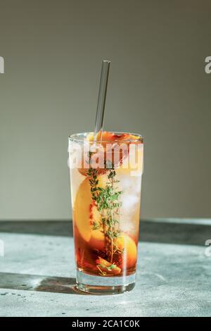 Rinfrescante tè freddo di pesca Cuba Libre o cocktail di tè freddo di Long Island in vetro con paglia. Bevanda estiva alla frutta rinfrescante. Messa a fuoco selettiva Foto Stock