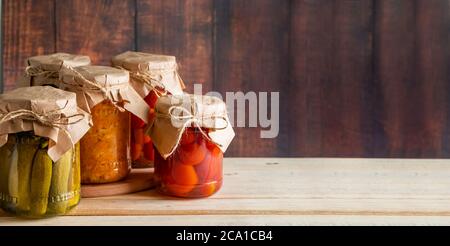 Vasetti di verdure fermentate su sfondo ligneo. Cetrioli in scatola fatti in casa, pomodori e crauti. Foto Stock