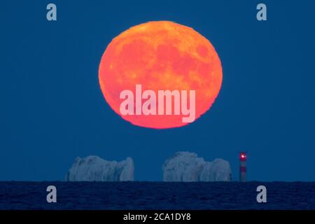 Mudeford, Dorset, Regno Unito. 3 agosto 2020. Regno Unito Meteo. La luna piena di Sturgeon illumina di arancione mentre si alza da dietro il faro di Needles sull'isola di Wight visto da Mudeford Quay in Dorset in una chiara serata estiva. Picture Credit: Graham Hunt/Alamy Live News Foto Stock