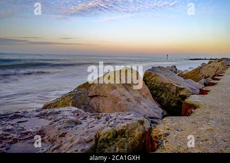 Una lunga esposizione che cattura le dolci onde che lambiscono la spiaggia sabbiosa di Cart Gap sulla costa nord del Norfolk Foto Stock