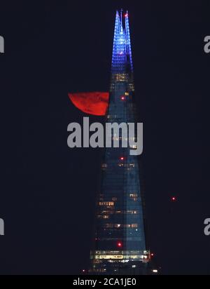 Una Luna piena, conosciuta come la Sturgeon Moon, è parzialmente vista da dietro le nuvole sopra l'edificio Shard a Londra. Foto Stock