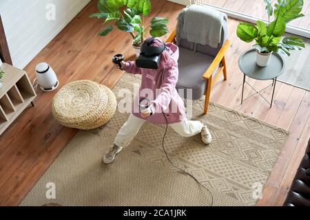 Teen girl rosa capelli indossare occhiali vr giocare gioco di realtà virtuale a casa, vista dall'alto. Foto Stock