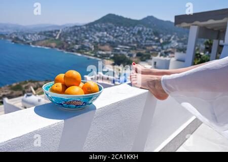 Gambe e arance donna sulla terrazza baconia della casa o hotel vista mare Foto Stock