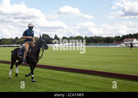 Egham, Regno Unito. 3 agosto 2020. Uno sposo che indossa una copertura per il viso per proteggere contro il coronavirus cavalca un cavallo lungo il lato di un campo di polo durante una partita di campionato della Cartier Queens Cup 2020 tra Next Generation e Segavas al Guards Polo Club di Windsor Great Park. La prossima generazione ha vinto la partita 11-9. Credit: Mark Kerrison/Alamy Live News Foto Stock