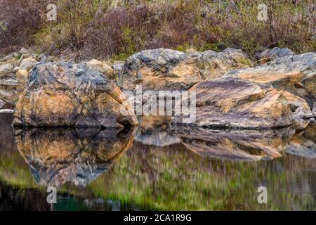 Granito precambriano riflesso in uno stagno di castoro in primavera, Cartier, Ontario, Canada Foto Stock