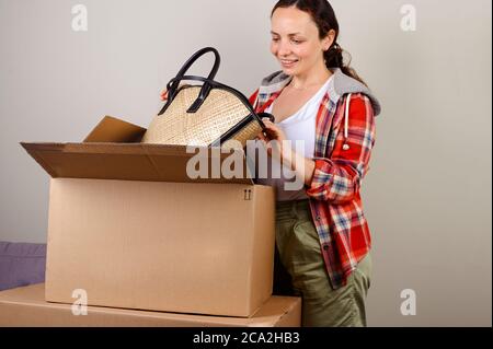 Disimballaggio del pacchetto Amazon. Una donna toglie il cappello e la borsa per la vacanza estiva. Concetto di mailing di successo, servizio per la casa e il business, acquisti online. Derisione. Spazio di copia Foto Stock