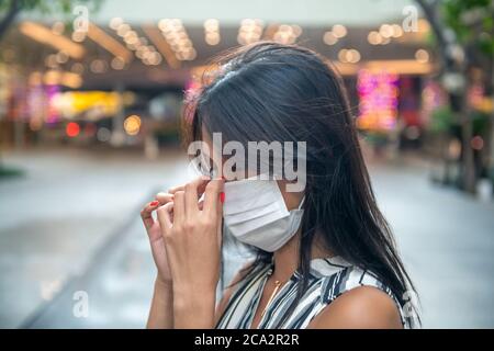 Giovane donna asiatica che viaggia in città indossando la maschera facciale. Foto Stock