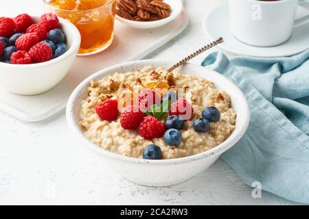 Porridge di farinata d'avena con mirtillo, lamponi, marmellata, vista laterale, primo piano. Dieta sana Foto Stock