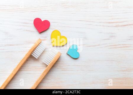 Due spazzolini da denti di bambù e tre cuori di legno su sfondo di legno d'epoca. Spazzolini biodegradabili in bambù. Prodotti naturali. Eco-friendly, zero wast Foto Stock