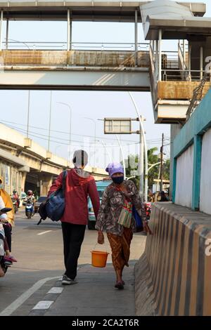 Giacarta / Indonesia - 25 luglio 2020. Venditori di erbe medicinali che stanno camminando intorno tenendo jamu e portando un secchio Foto Stock