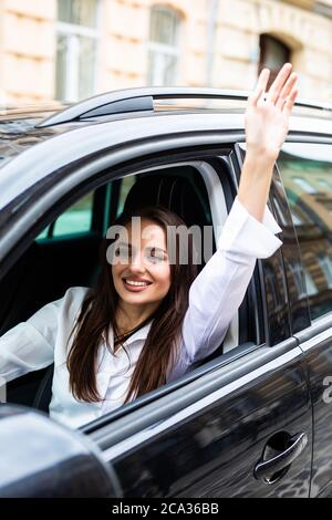 Ragazza felice in macchina con le mani in su. Divertirsi mentre si guida l'auto Foto Stock