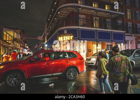 New Orleans - 05/01/2018: Vita notturna lungo Bourbon Street nel quartiere francese - una macchina rossa attraversa la strada Foto Stock