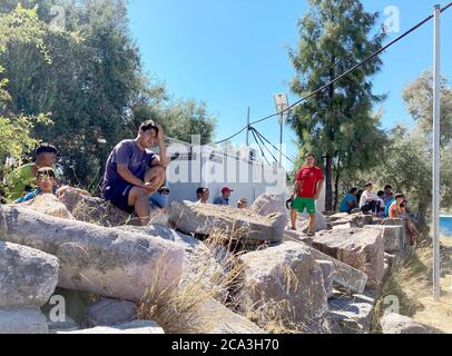 Lesbos, Grecia. 04 agosto 2020. I rifugiati afghani siedono su pietre a Camp Kara Tepe. Laschet (CDU), primo ministro della Renania Settentrionale-Vestfalia, sta visitando il campo profughi sull'isola di Lesbos come parte di una gita di diversi giorni in Grecia. Credit: Hülsmeier/dpa/Alamy Live News Foto Stock