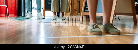 Persone irriconoscibili che si accodano mantenendo la distanza sociale Foto Stock