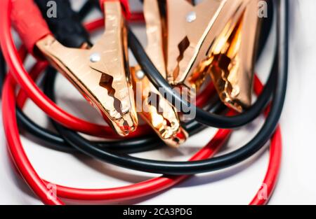 Primo piano del cavo di collegamento rosso e nero della batteria dell'auto, isolato su sfondo bianco. Cavo di sovralimentazione. Concentrarsi sul metallo Foto Stock