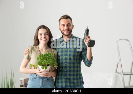 Ritratto di giovane coppia allegra abbracciando in un nuovo appartamento e preparandosi per il rimodellamento dopo il trasferimento Foto Stock