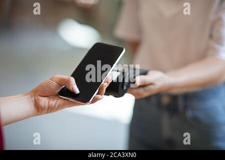 Pagamento wireless. Primo piano mano femminile utilizzando smartphone, pagando senza contatto al bar Foto Stock