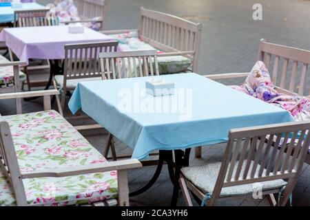 caffè all'aperto con tavoli e panchine in legno coperti di morbidi cuscini e tovaglie, nessuno. Foto Stock