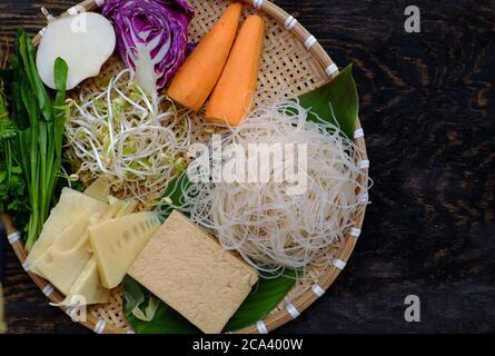 Vassoio di materie prime zuppa di tagliatelle vegane, verdure colorate come carote, germogli di fagioli, bocce di bambù, tofu, semplice piatto vietnamita sano, nutrizione Foto Stock