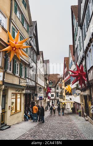 Atmosfera tranquilla nei vicoli medievali di ciottoli di Tubingen. La gente cammina tra i tipici edifici tedeschi a graticcio con tetto spiovente - Tübingen, Germania Foto Stock