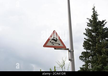 Auto segnale stradale Skid Guida strada sicurezza del traffico attaccato a barra di alluminio contro il cielo piovoso e nei pressi di un albero nella campagna svizzera. Foto Stock