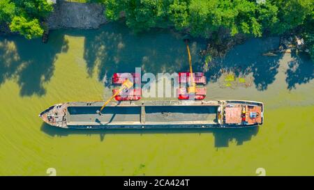 La vista aerea sul drago dell'escavatore è dragante, lavorando sul fiume, sul canale, l'approfondimento e la rimozione dei sedimenti, fango dal letto del fiume in un canale inquinato. Foto Stock