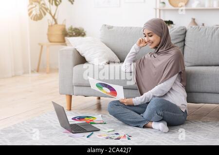 Corsi di Design online. Arab Woman con gamma di colori e notebook a casa Foto Stock