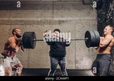 una donna obesa piacevole sta prendendo un selfie per mostrare ai suoi amici che lei può sollevare il barbell. ragazza sovrappeso che gioca scherzi con i suoi amici Foto Stock