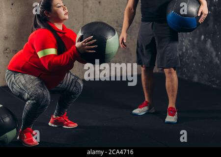 fat ragazza facendo sedersi su al centro sportivo. vista laterale shot Foto Stock