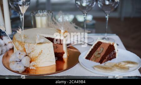 Bella torta di nozze cioccolato con crema di cioccolato all'interno e banana ripieno, pezzo di torta su un piatto. Torta bianca con un decor. Foto Stock