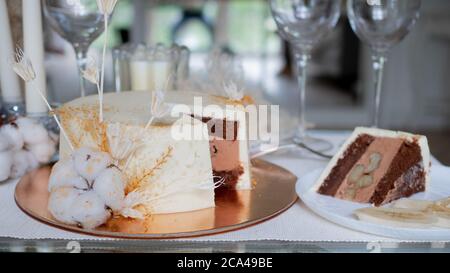 Bella torta di nozze cioccolato con crema di cioccolato all'interno e banana ripieno, pezzo di torta su un piatto. Torta bianca con decorazioni in cotone. Foto Stock