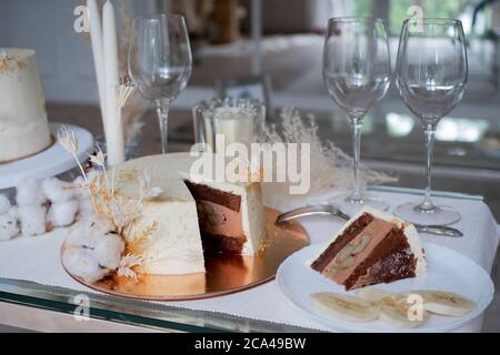 Bella torta di nozze cioccolato con crema di cioccolato all'interno e banana ripieno, pezzo di torta su un piatto. Torta bianca con un decor. Foto Stock