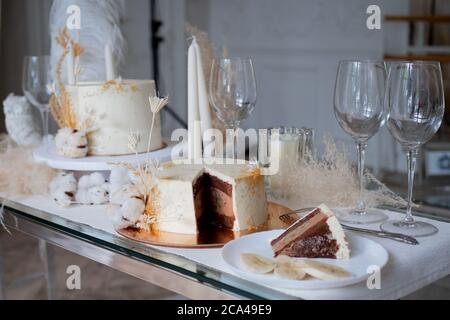 Bella torta di nozze cioccolato con crema di cioccolato all'interno e banana ripieno, pezzo di torta su un piatto. Torta bianca con un decor. Foto Stock