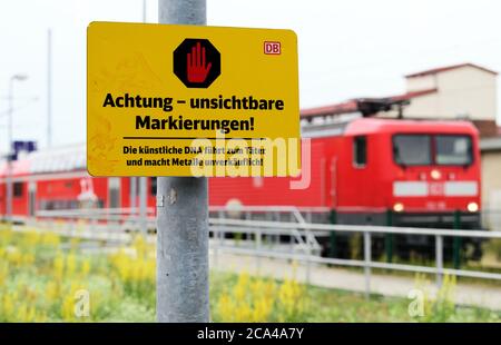 02 agosto 2020, Brandeburgo, Golßen: Un segno con l'iscrizione 'attenzione - segni invisibili! Il DNA artificiale conduce al perpetuatore e rende i metalli non vendibili' è scritto vicino alla stazione accanto alle piste ferroviarie. Foto: Soeren Stache/dpa-Zentralbild/dpa Foto Stock