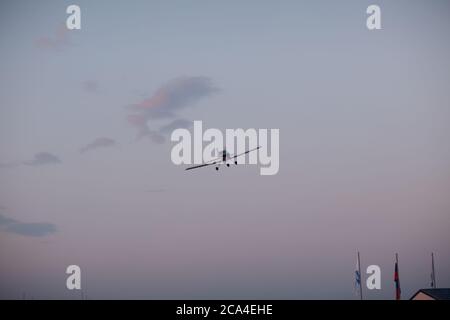 Piccolo aeroplano a motore singolo che vola contro il cielo del tramonto Foto Stock