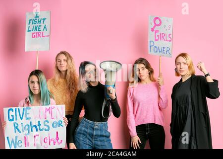 ritratto di donne fiduciose che lottano per i diritti delle donne tenendo manifesti con iscrizioni isolate su sfondo rosa, indipendenza e femminismo conce Foto Stock