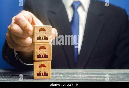 Il leader aziendale costruisce un blocco tower con i dipendenti. Team building, sistema verticale di potenza gerarchico. Leadership. Gestione efficace del team. Azienda Foto Stock