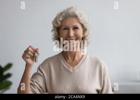 Donna anziana felice che tiene mazzo di chiavi guardando la macchina fotografica Foto Stock
