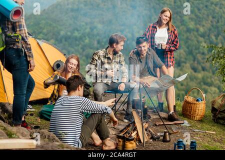 impressionanti escursionisti allegri che pianificano il loro viaggio, mentre si siedono nel camp.leisure, passatime Foto Stock