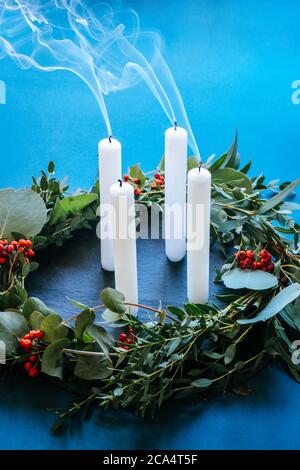 Moderna corona di Natale dell'Avvento con foglie di eucalipto e 4 candele bianche soffiate, ancora fumanti Foto Stock