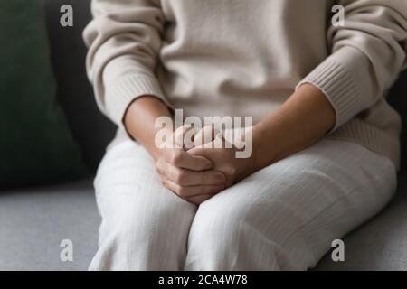 La donna anziana solitaria ha messo le mani sui giri seduti sul divano Foto Stock