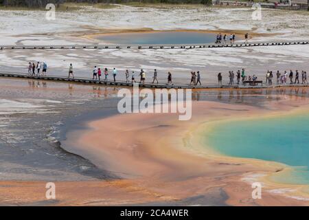 I visitatori camminano lungo la passerella presso la Grand Prismatic Spring lunedì 3 agosto 2020. Molti dei passerelle dei parchi sono stati realizzati in modo unidirezionale per combattere la trasmissione del virus COVID-19. Il parco ha recentemente segnalato diversi casi positivi del virus COVID-19 tra visitatori e concessionari. Foto Stock