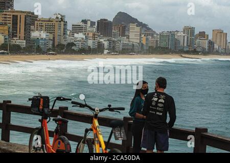 Rio de Janeiro, Brasile 21 maggio 2020 UNA coppia che indossa maschere Godetevi il sole alla spiaggia di Leblon Foto Stock