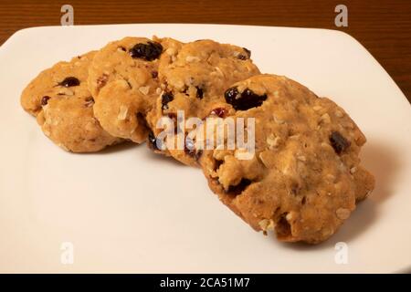AVENA, MIRTILLI ROSSI, BISCOTTI DI MIRTILLI ROSSI SU UN PIATTO BIANCO Foto Stock