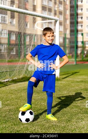 un piccolo giocatore di calcio con una palla si trova su un campo di calcio verde nel gol Foto Stock