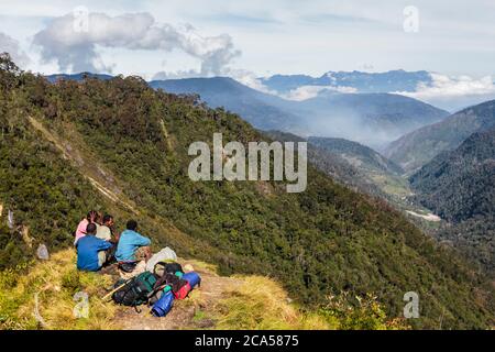 Indonesia, Papua, valle di Baliem, vicino a Walena, Yali territorio della gente, sentiero escursionistico a Angguruk, Siam passo, guida e facchini fare una pausa mentre si guarda Foto Stock