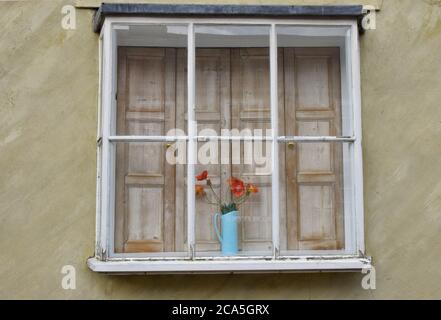 caraffa di fiori e persiane in legno nella finestra Foto Stock