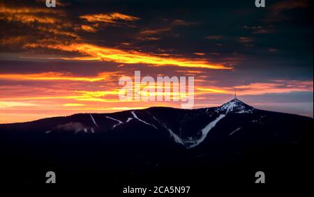 Cielo scenografico al tramonto con nuvole illuminate in montagna. Silhouette nera scura di cresta di montagna e torre del trasmettitore di Jested alla parte inferiore, scura Foto Stock