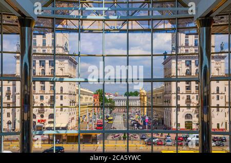 Minsk, Bielorussia, 26 luglio 2020: Porte di Minsk due torri alte Classicismo socialista edifici in stile Stalin Impero attraverso vetrate della stazione ferroviaria e piazza con auto a cavallo e autobus Foto Stock