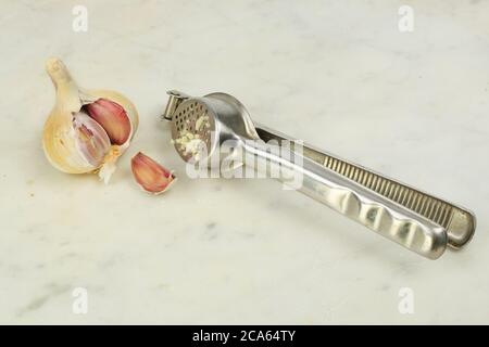 Bulbo d'aglio e spicchio con una grattugia su una superficie di lavoro in marmo Foto Stock
